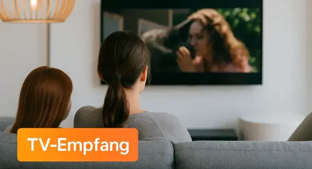Rückansicht zweier Frauen auf dem Sofa sitzend mit Blick in Richtung TV-Gerät an die Wand montiert